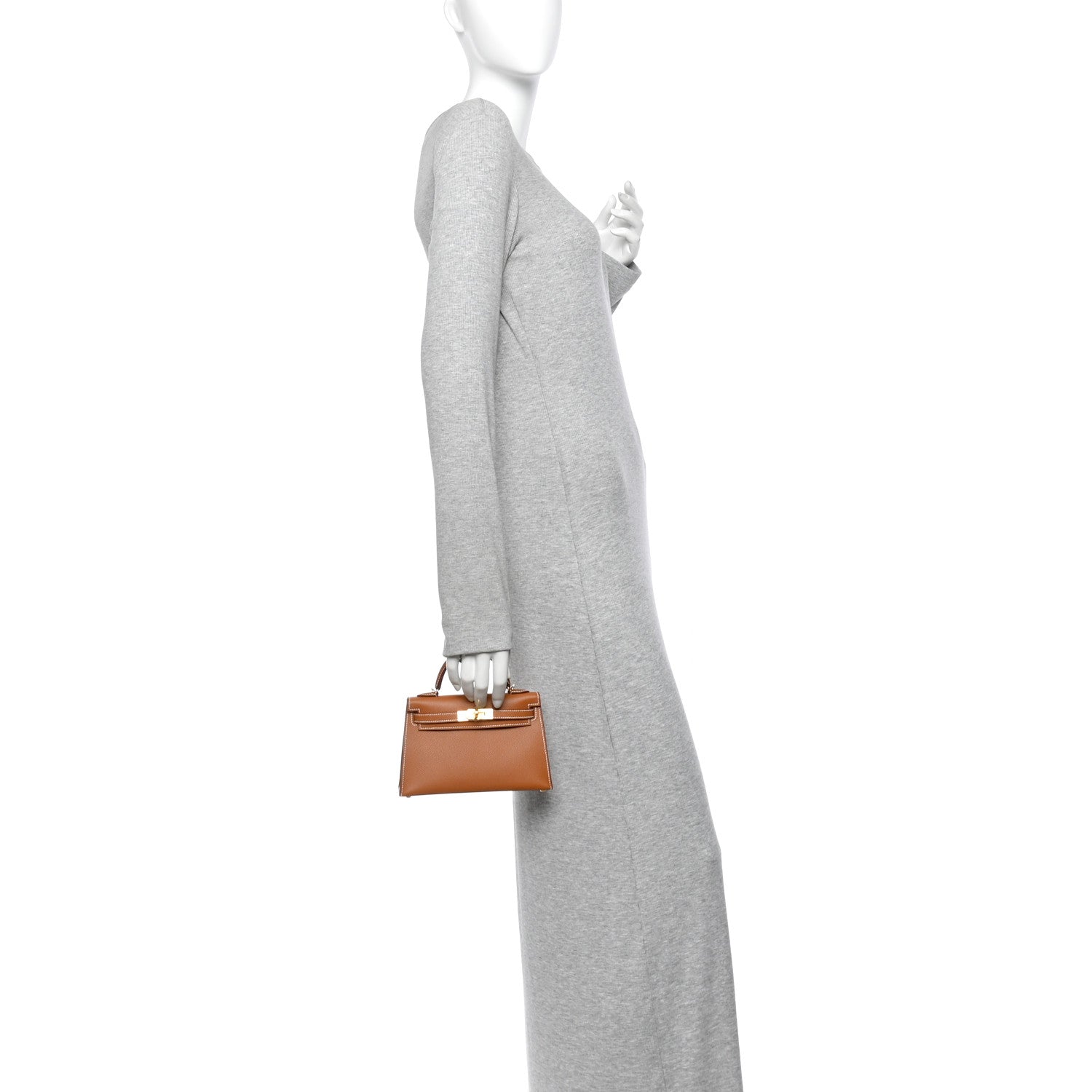 Gold Epsom Hermès Mini Kelly II held by the handle on a mannequin, showing its small size